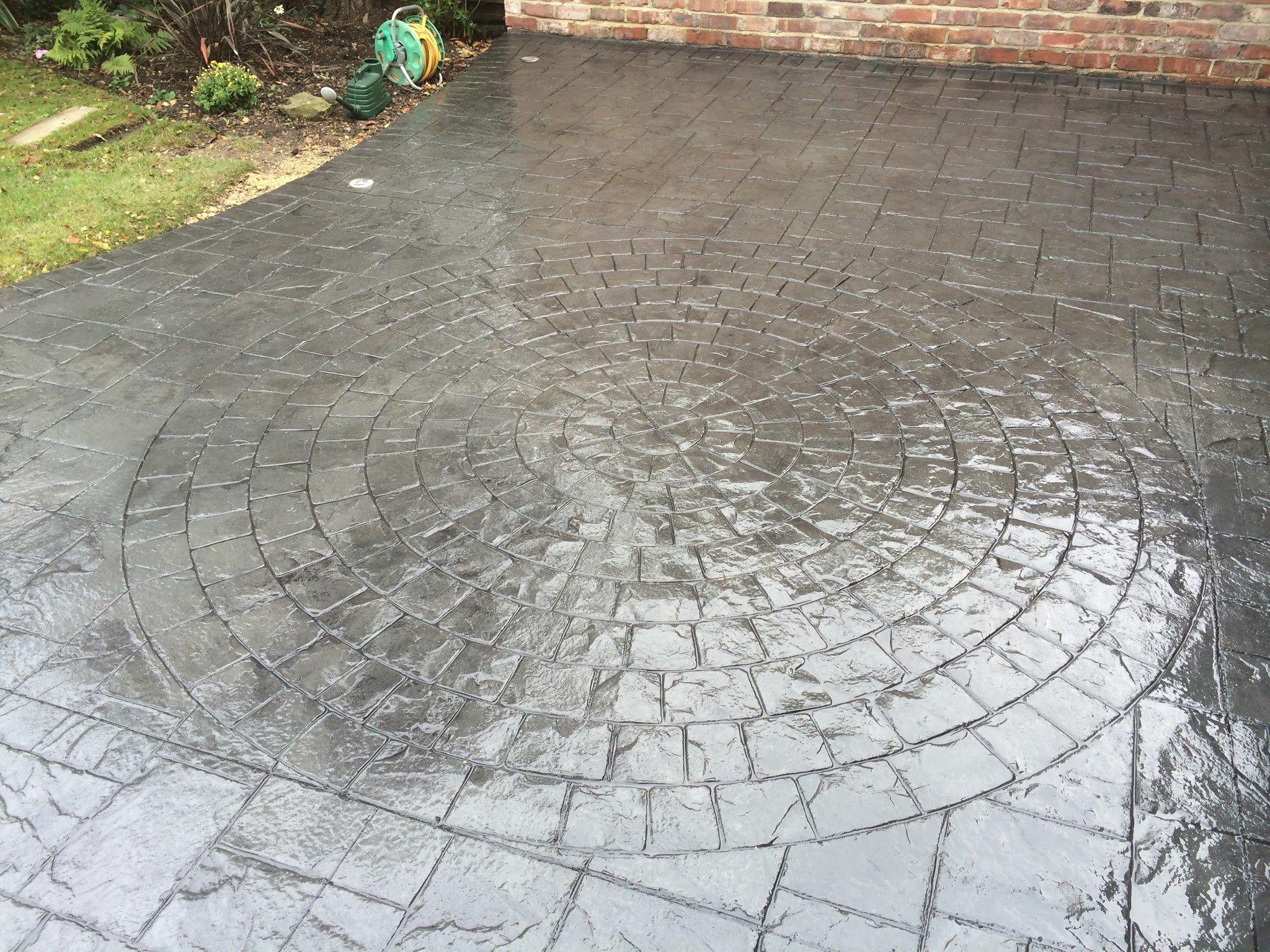Grey cobble-print driveway with a large circle feature, freshly sealed