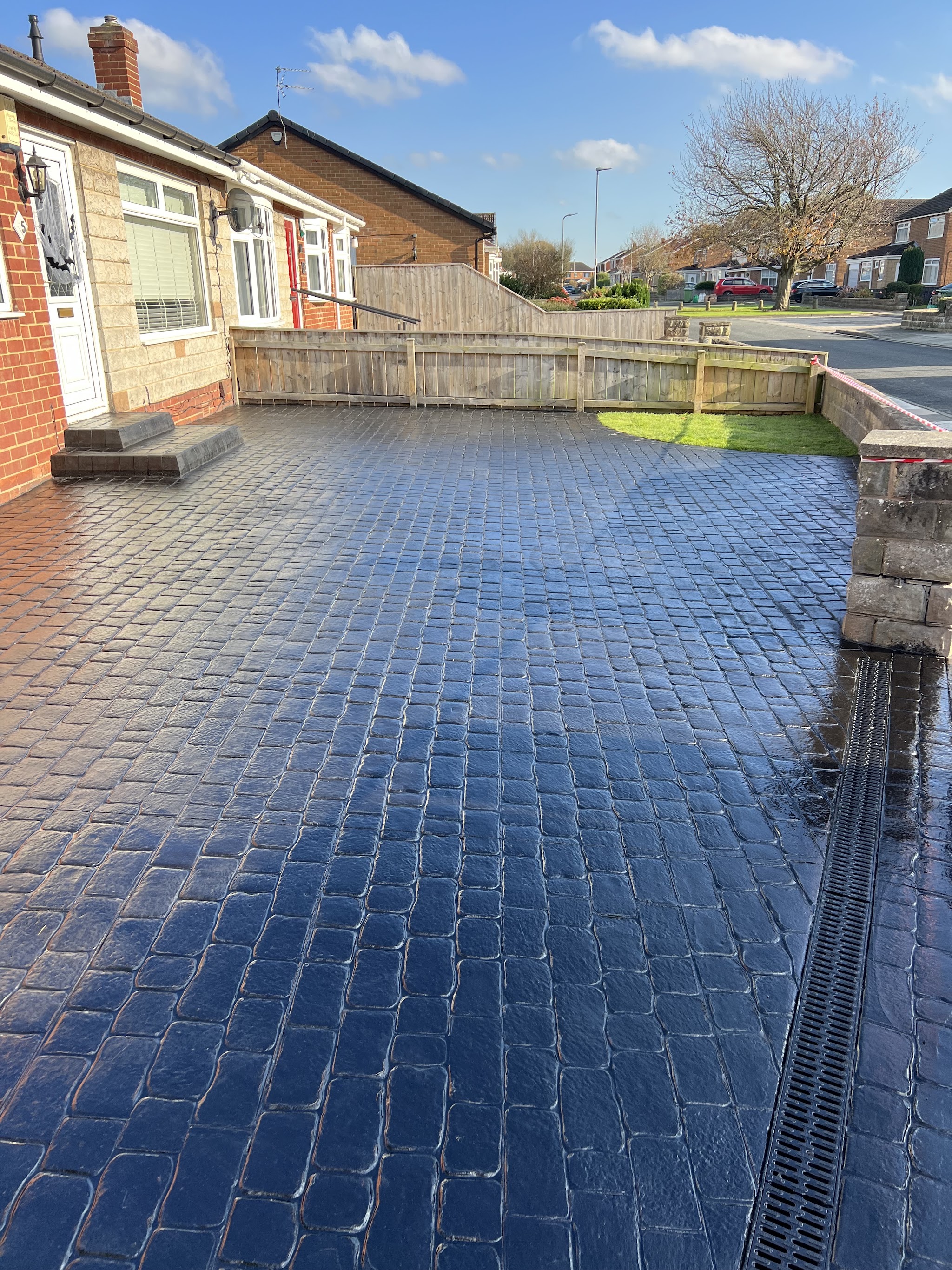 Dark cobble-print driveway with a drainage channel beside a bungalow