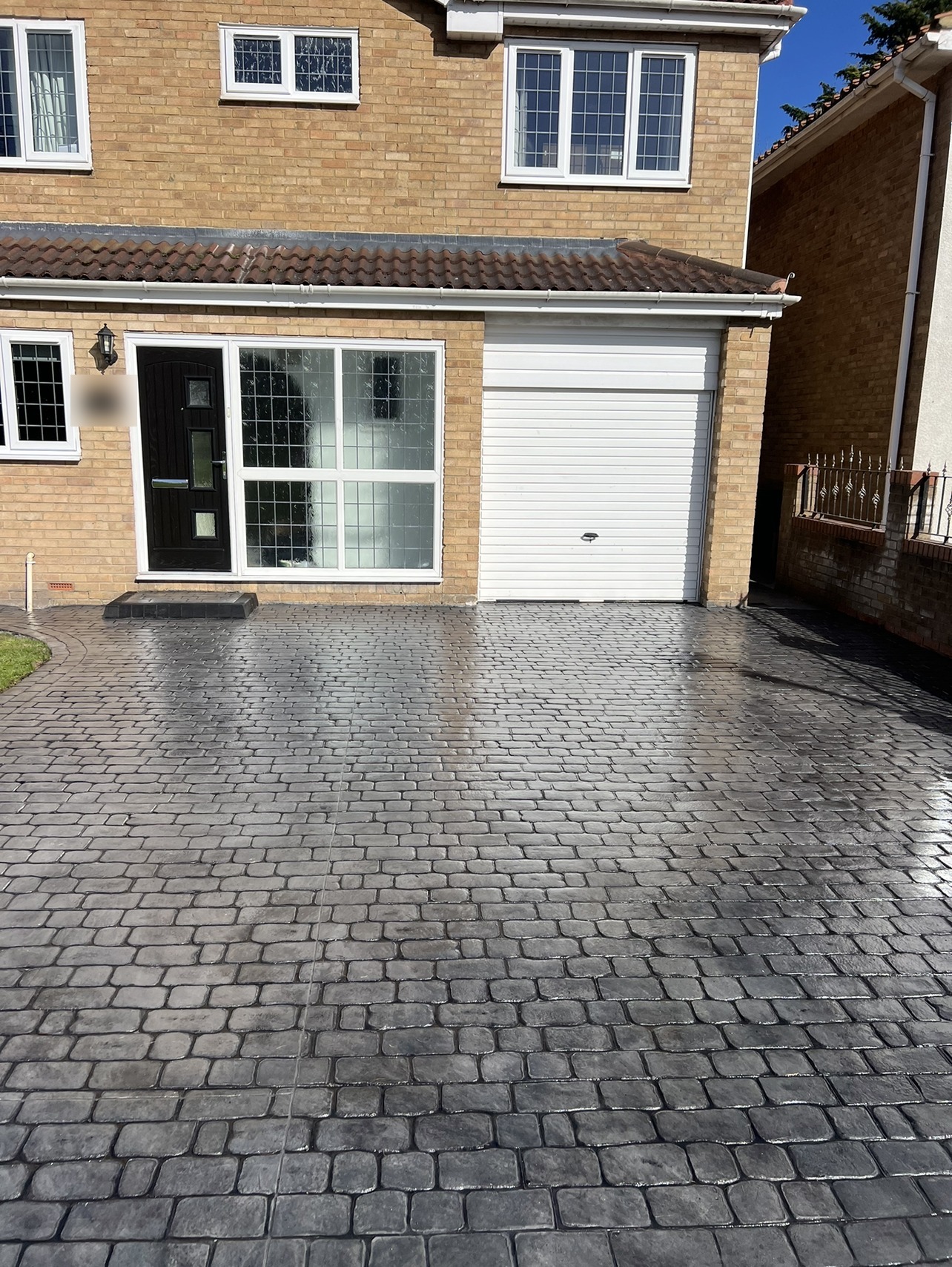 Charcoal cobble-print driveway laid in front of a house and garage