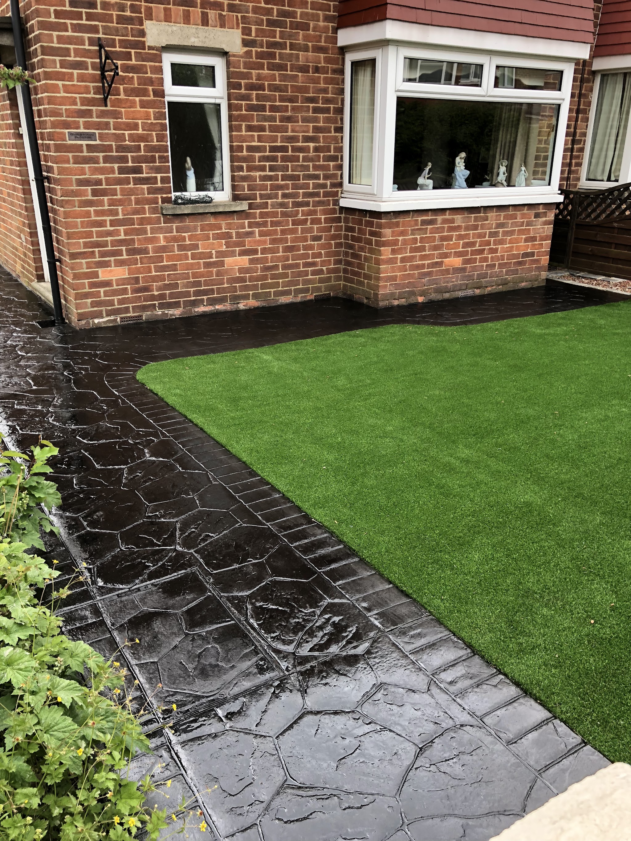 Dark printed path running beside new artificial grass at the front of a house