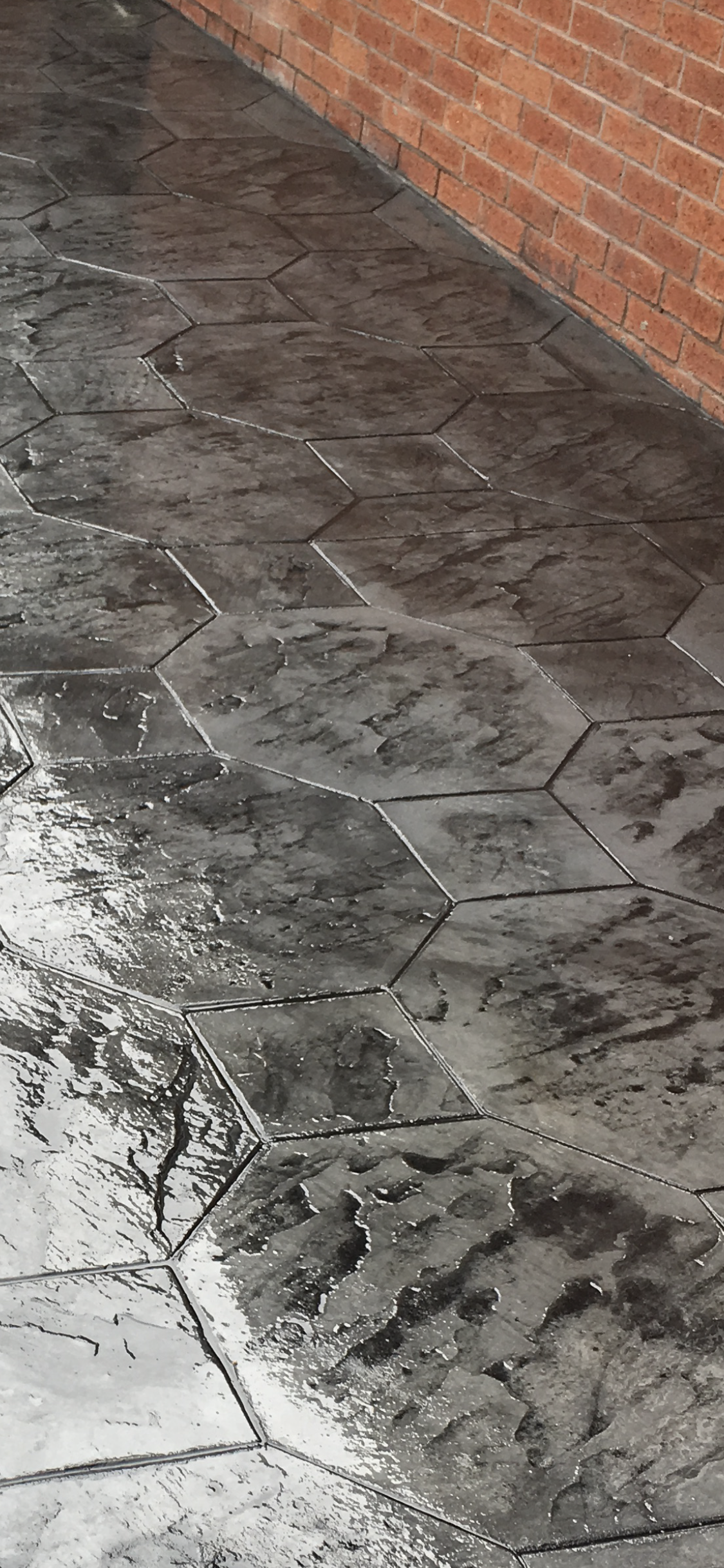 Close-up of a grey hexagon-print surface against brickwork